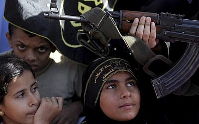 Palestinian children sit next to a woman holding a gun during an Islamic Jihad rally in Gaza City (photo credit: AP/Hatem Moussa)
