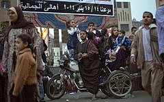 An Egyptian family sit on a motorbike under a banner with Arabic writing that reads,"Go down, participate and say yes for Egypt's constitution and no for terrorism," as they watch a march to mark the birthday of the Prophet Muhammad in Cairo, Egypt, Monday, January 13, 2014. (photo credit: AP Photo/Khalil Hamra)
