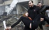 A Lebanese man carries an injured woman away from the site of a car bomb explosion in Beirut on Thursday January 2, 2014. (photo credit: AP/Hussein Malla)