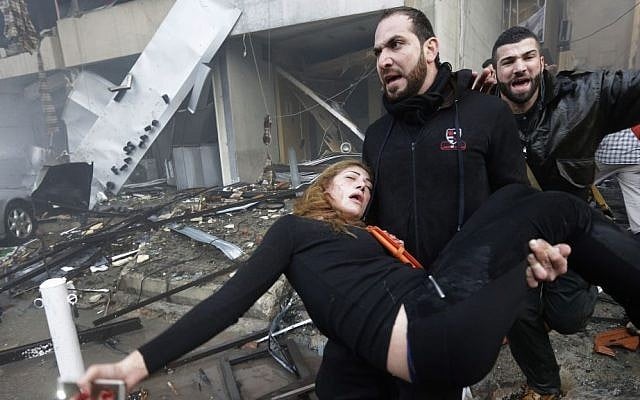 A Lebanese man carries an injured woman away from the site of a car bomb explosion in Beirut on Thursday January 2, 2014. (photo credit: AP/Hussein Malla) A Lebanese man carries an injured woman away from the site of a car bomb explosion in Beirut on Thursday January 2, 2014. (photo credit: AP/Hussein Malla)