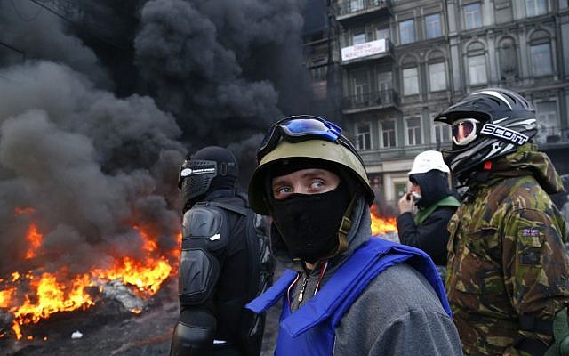 Protesters stand behind the barricade in front of riot police in central Kiev, Ukraine, on January 25, 2014. (photo credit: AP/Sergei Grits) Protesters stand behind the barricade in front of riot police in central Kiev, Ukraine, on January 25, 2014. (photo credit: AP/Sergei Grits)
