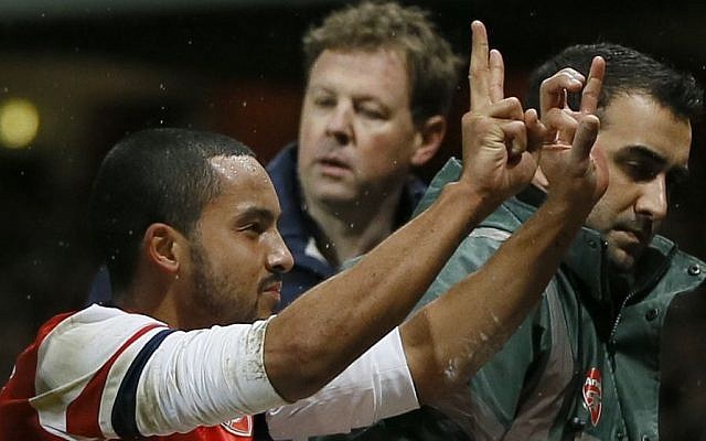 Arsenal's Theo Walcott gestures to the crowd to show the score of 2-0, as he is stretchered off in front of Tottenham fans during the English FA Cup third round soccer match between Arsenal and Tottenham Hotspur at the Emirates Stadium in London, Saturday, Jan. 4, 2014. Arsenal won the match 2-0. (photo credit: AP Photo/Kirsty Wigglesworth) Arsenal's Theo Walcott gestures to the crowd to show the score of 2-0, as he is stretchered off in front of Tottenham fans during the English FA Cup third round soccer match between Arsenal and Tottenham Hotspur at the Emirates Stadium in London, Saturday, Jan. 4, 2014. Arsenal won the match 2-0. (photo credit: AP Photo/Kirsty Wigglesworth)