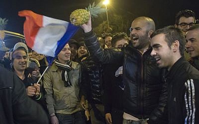 People wave a French flag and hold a pineapple outside the Zenith arena where French comic Dieudonne's show was banned in Nantes, France, Thursday, Jan. 9, 2014. France’s top administrative body turned the tables on Dieudonne, ruling in an urgent decision that his Thursday night show could not take place. The decision by the Council of State in Paris overturned a Nantes court ruling hours earlier that had annulled the ban the city had imposed on the show by Dieudonne M’Bala M’Bala. The comic was convicted last fall for using the word "Shoananas," a mash-up of the Hebrew word for Holocaust and the French word for pineapple. (photo credit: AP Photo/Michel Euler)