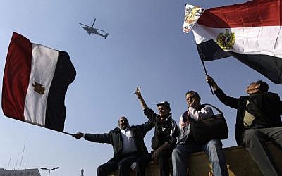 Egyptians wave national flags as they greet an army helicopter flying over Tahrir Square, the focal point of Egyptian uprising, in Cairo, Egypt, Saturday, Jan. 25, 2014. (AP Photo/Amr Nabil)