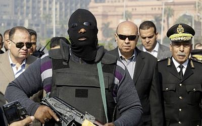 An Egyptian masked policeman guards Cairo's state security chief, Osama al-Saghir, third right, as he visits Tahrir Square, the epicenter of the 2011 uprising, in Cairo, Egypt, Saturday, Jan. 25, 2014. (AP Photo/Amr Nabil)