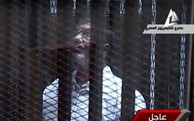 Toppled President Mohammed Morsi stands inside a glass-encased metal cage in a courtroom in Cairo, Tuesday, Jan. 28. 2014.  (photo credit: AP/Egyptian State TV)