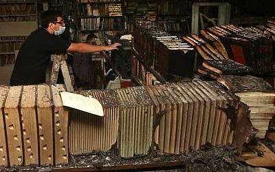 A Lebanese activist removes burned books, at the Saeh (Tourist) Library which was set on fire by masked men, in the northern city of Tripoli, Lebanon, January 2014. (AP Photo/Hussein Malla)