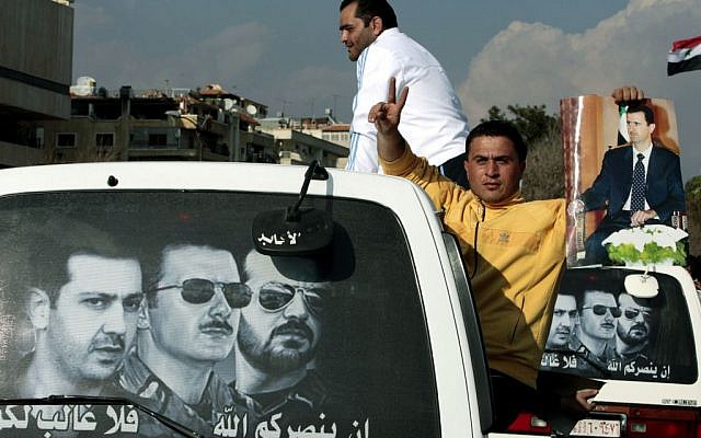A pro-Syrian President Bashar Assad protester holds Assad's poster as he sits outside a mini van window during a pro-Assad demonstration, in Damascus, Syria, March 25, 2011 (photo credit: AP/Hussein Malla, file) A pro-Syrian President Bashar Assad protester holds Assad's poster as he sits outside a mini van window during a pro-Assad demonstration, in Damascus, Syria, March 25, 2011 (photo credit: AP/Hussein Malla, file)