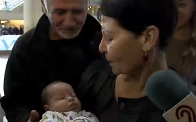 Edna Lanchet holds her new grandson for the first time, at Ben Gurion International Airport, on Friday (photo credit: screenshot Channel 2)