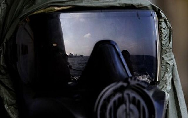 A crew member of the Danish warship Esbern Snare wears a protective mask which shows the reflection of the Danish cargo ship Ark Futura, during emergency drills on the sea between Cyprus and Syria, Sunday, Jan. 5, 2014 (photo credit: AP/Petros Karadjias) A crew member of the Danish warship Esbern Snare wears a protective mask which shows the reflection of the Danish cargo ship Ark Futura, during emergency drills on the sea between Cyprus and Syria, Sunday, Jan. 5, 2014 (photo credit: AP/Petros Karadjias)
