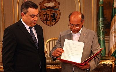 Interim Prime Minister, Mehdi Jomaa, left, presents the list of the members of his government to Tunisian President Moncef Marzouki during the new government presentation ceremony at the presidential palace in Carthage near Tunis, Sunday, Jan. 26, 2014. Tunisia's interim prime minister announced on Sunday his new government following a 24-hour delay over the post of interior minister. Mehdi Jomaa, the interim prime minister, had been working since Jan. 10 to form a government of technocrats to guide the country to new elections after a political crisis that began last year between Islamists and the opposition following the assassination of an opposition politician. (photo credit: AP/Hassene Dridi)