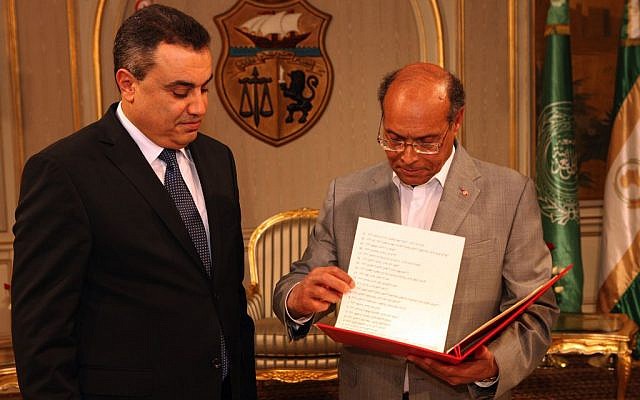 Interim Prime Minister, Mehdi Jomaa, left, presents the list of the members of his government to Tunisian President Moncef Marzouki during the new government presentation ceremony at the presidential palace in Carthage near Tunis, Sunday, Jan. 26, 2014. Tunisia's interim prime minister announced on Sunday his new government following a 24-hour delay over the post of interior minister. Mehdi Jomaa, the interim prime minister, had been working since Jan. 10 to form a government of technocrats to guide the country to new elections after a political crisis that began last year between Islamists and the opposition following the assassination of an opposition politician. (photo credit: AP/Hassene Dridi) Interim Prime Minister, Mehdi Jomaa, left, presents the list of the members of his government to Tunisian President Moncef Marzouki during the new government presentation ceremony at the presidential palace in Carthage near Tunis, Sunday, Jan. 26, 2014. Tunisia's interim prime minister announced on Sunday his new government following a 24-hour delay over the post of interior minister. Mehdi Jomaa, the interim prime minister, had been working since Jan. 10 to form a government of technocrats to guide the country to new elections after a political crisis that began last year between Islamists and the opposition following the assassination of an opposition politician. (photo credit: AP/Hassene Dridi)
