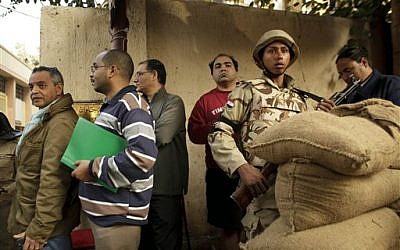 An Egyptian army soldier stands guard as voters line up outside a polling station for the first day in the country's constitutional referendum in the upscale neighborhood of Zamalek in Cairo, Egypt, Tuesday, January 14, 2014.  (photo credit: AP/Maya Alleruzzo)