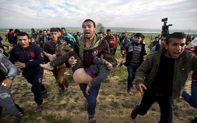 Palestinian protesters in the Gaza Strip carry an injured boy during clashes with Israeli security forces along the border fence. (photo credit: Mahmud Hams/AFP) Palestinian protesters in the Gaza Strip carry an injured boy during clashes with Israeli security forces along the border fence. (photo credit: Mahmud Hams/AFP)