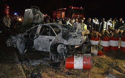 Lebanese emergency personnel and security forces gather around a burnt out vehicle at the site of a bomb explosion that targeted an army post on February 22, 2014 in eastern Lebanon's town of Hermel. (Photo credit: AFP/STR)