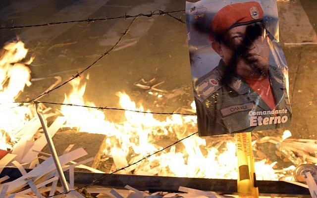 A poster of Venezuelan late President Hugo Chavez remains near a burning barricade during an anti-government demo, in Caracas on February 21, 2014. (photo credit: AFP/Leo Ramirez) A poster of Venezuelan late President Hugo Chavez remains near a burning barricade during an anti-government demo, in Caracas on February 21, 2014. (photo credit: AFP/Leo Ramirez)