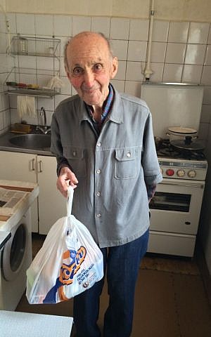 Mihail Solomonovich holding a food package delivered by JDC in the kitchen of his modest one-bedroom apartment in downtown Kiev. (photo courtesy of the JDC) Mihail Solomonovich holding a food package delivered by JDC in the kitchen of his modest one-bedroom apartment in downtown Kiev. (photo courtesy of the JDC)