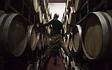 In this Tuesday, February 11, 2014 photo, Israeli workers inspect barrels in a winery in the West Bank settlement of Psagot. (photo credit: AP/Dan Balilty)