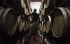 In this photo from February 11, 2014, Israeli workers inspect barrels in a winery in the West Bank settlement of Psagot. (AP/Dan Balilty)