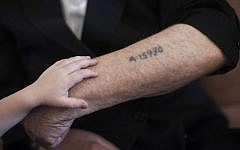 A little boy puts a hand on his grandfather's arm near his concentration camp prisoner number tattoo, in Jerusalem on May 24, 2013. (photo credit: Yonatan Sindel/Flash90)