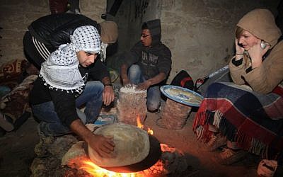 Palestinian and foreign activists warm themselves beside a fire at the site of the old village known as Ein Hijleh, in the Jordan valley near the West Bank City of Jericho February 04, 2014. (photo credit: Issam RiImawi/Flash90)