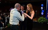 Cpt. Ziv Shilon places a ring on Adi Sitbon's finger at an FIDF event in Hollywood, Florida, on Thursday (photo credit: Carlos Chattah/JTA)