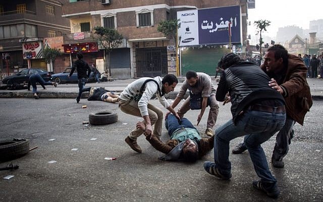 A mortally wounded supporter of Egypt's ousted Islamist president is evacuated as another wounded protester lies in the street during clashes with security forces in the Mohandiseen district of Cairo, Egypt. January 25, 2014. (photo credit: AP Photo/Eman Helal, File)