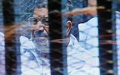 Egypt's ousted president Mohammed Morsi in a soundproof barred glass cage is seen on a monitor. Morsi and 35 others are facing charges of conspiring with foreign groups and undermining national security. (AP Photo/Mohammed al-Law, File)