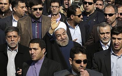 Escorted by his bodyguards, Iranian President Hassan Rouhani, center, waves to his well wishers as he attends an annual rally commemorating the anniversary of the 1979 Islamic revolution, in Tehran, Iran, on Tuesday, February 11, 2014. (photo credit: AP Photo/Vahid Salemi)