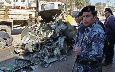 In this Thursday, Feb. 6, 2014 file photo, civilians and security forces inspect the site of a car bomb attack in the Shaab neighborhood of Baghdad, Iraq. Car bombs are one of the deadliest weapons used by the al-Qaeda breakaway group that dominates the Sunni insurgency in Iraq, with coordinated waves of explosions regularly leaving scores dead in Baghdad and elsewhere across the country. (photo credit: AP Photo/Karim Kadim, File)
