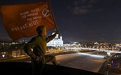 A man dressed in WWII-era Soviet Army uniform holds a replica of Soviet Victory Flag on a roof of TV Rain headquarters late Monday during a protest picket in Moscow. Several Russian cable and satellite providers have removed a top independent television channel from their packages after it ran a poll asking the audience if the Soviets should have surrendered Leningrad to the Nazis to avoid more than a million deaths during the WWII siege. (AP Photo/Mikhail Dukhovich)