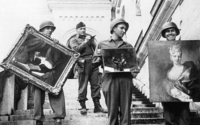 This photo provided by The Monuments Men Foundation for the Preservation of Art of Dallas, shows Monuments Man James Rorimer, with notepad, as he supervises American GI's hand-carrying paintings down the steps of the castle in Neuschwanstein, Germany in May of 1945. (photo credit: AP/National Archives and Records Administration)