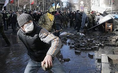 Anti-government protesters lob stones during clashes with riot police outside Ukraine's parliament in Kiev, Ukraine, Tuesday, Feb. 18, 2014. (AP Photo/Efrem Lukatsky)