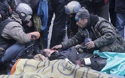 An activist closes a victim's eyes while others pay respects to protesters who were killed in clashes with police in Kiev's Independence Square, the epicenter of the country's current unrest, Thursday, February 20, 2014 (photo credit: AP/Efrem Lukatsky)