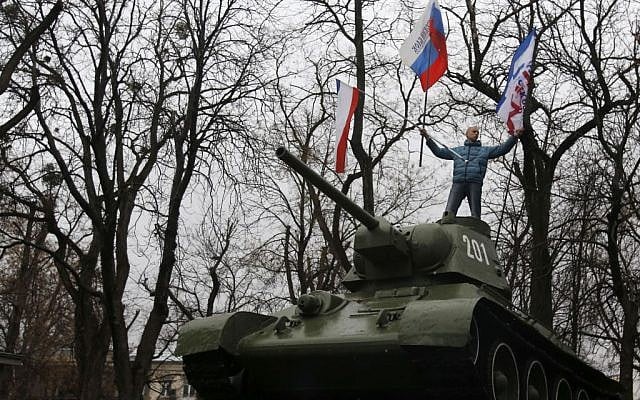 A Pro-Russian demonstrator waves Russian and Crimea flags from an old Soviet Army tank during a protest in front of a local government building in Simferopol, Crimea, Ukraine, on Thursday, February 27, 2014. (photo credit: AP Photo/Darko Vojinovic) A Pro-Russian demonstrator waves Russian and Crimea flags from an old Soviet Army tank during a protest in front of a local government building in Simferopol, Crimea, Ukraine, on Thursday, February 27, 2014. (photo credit: AP Photo/Darko Vojinovic)