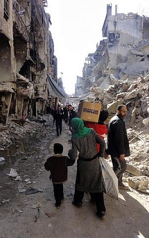 Residents of Syria's besieged Yarmouk Palestinian refugee camp carry food parcels, February 1, 2014 (photo credit: UNRWA/AFP)
