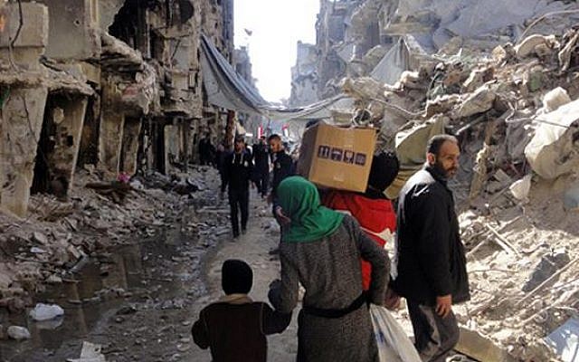Residents of Syria's besieged Yarmouk Palestinian refugee camp carry food parcels, February 1, 2014 (photo credit: UNRWA/AFP) Residents of Syria's besieged Yarmouk Palestinian refugee camp carry food parcels, February 1, 2014 (photo credit: UNRWA/AFP)