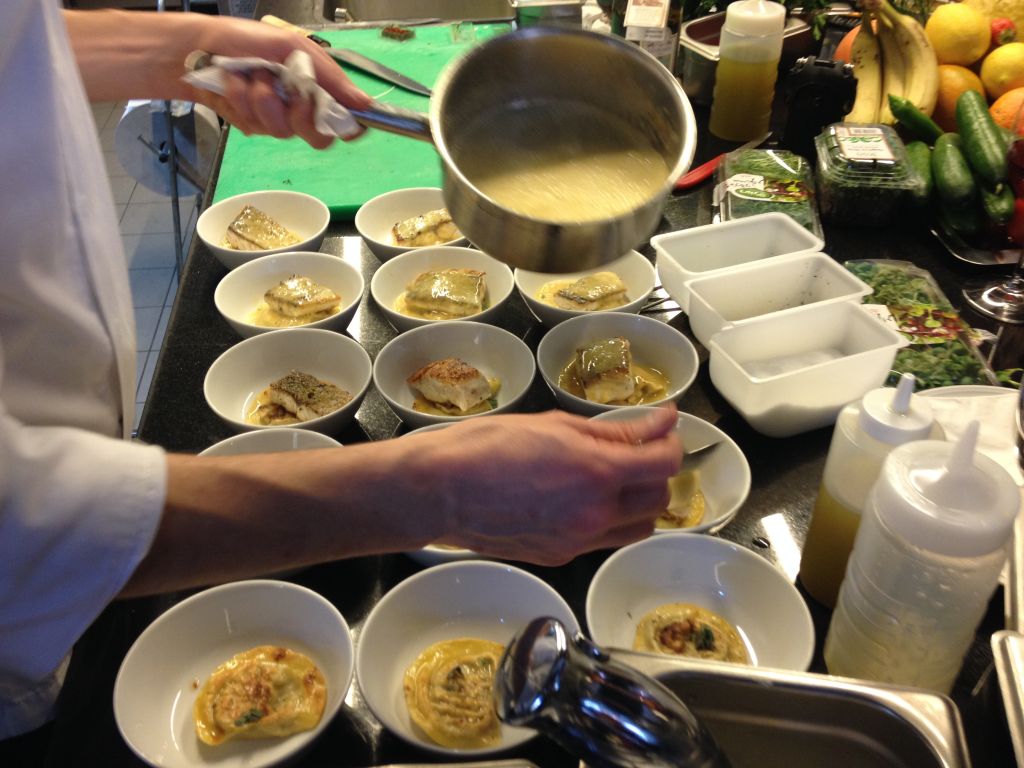 Spooning some sauce on crisped sea bream and ravioli (photo credit: Jessica Steinberg/Times of Israel)
