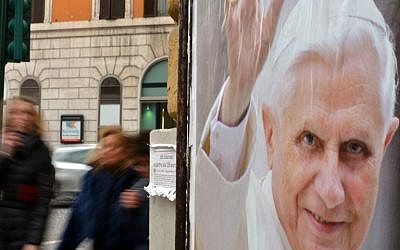 People pass by a placard in Rome, homage to Pope Benedict XVI (photo credit: AFP/File Gabriel Bouys)