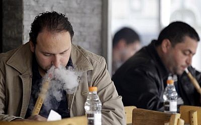 Men smoke traditional water pipes at an outdoor cafe in the Jordanian capital Amman on February 3, 2014. (photo credit: AFP/Khalil Mazraawi)