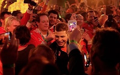 Under orange lighting, gold medallist Sven Kramer of the Netherlands walks through a crowd of cheering fans after winning the gold in the men's 5,000-meter speedskating race at the 2014 Winter Olympics in Sochi, Russia, Saturday, Feb. 8, 2014. (AP Photo/Matt Dunham)