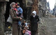 Residents of the besieged Yarmouk Palestinian refugee camp wait to leave the camp, on the southern edge of the Syrian capital Damascus, Syria, Feb. 4, 2014 (photo credit: AP/SANA)