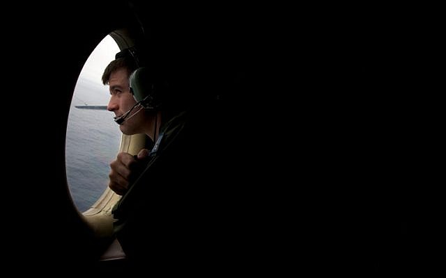 A crewman of an RAAF AP-3C Orion aircraft looks out his observation window whilst searching for the missing Malaysia Airways Flight MH370 over the Indian Ocean on March 24, 2014.  (photo credit: AFP/POOL/RICHARD WAINWRIGHT)
