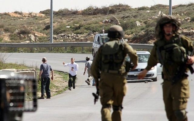 Israeli soldiers are seen close to settlers who appear to attack a photographer's car, near the West Bank settlement of Beit El, on March 7, 2014. (AFP) Israeli soldiers are seen close to settlers who appear to attack a photographer's car, near the West Bank settlement of Beit El, on March 7, 2014. (AFP)