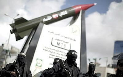 Members of theHamas's armed wing, stand in front of a model of a Gaza Strip-made M75 rocket newly displayed at the al-Jalaa square on March 10, 2014 in Gaza City. ( AFP photo/Mahmud Hams)