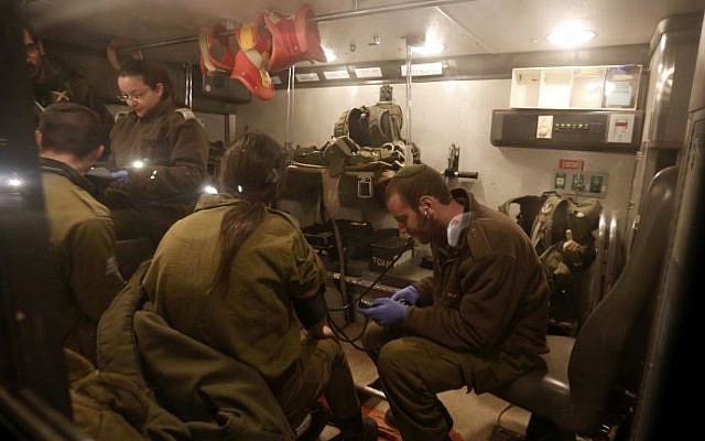 Israeli military medics examine comrades in an ambulance near Har Dov, on Israel's northern border with Lebanon, March 14, 2014 (photo credit: AFP/Jalaa Marey) Israeli military medics examine comrades in an ambulance near Har Dov, on Israel's northern border with Lebanon, March 14, 2014 (photo credit: AFP/Jalaa Marey)