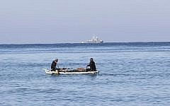 Palestinian fishermen sit in their boat off the shores of the southern Gaza Strip town of Rafah, as an Israeli police boat is seen in the distance, March 26, 2014. (AFP/Said Khatib)