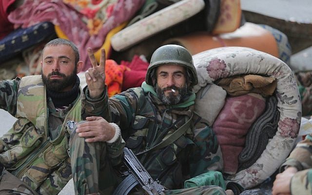 A pro-government forces member flashes the "V-sign" for victory next to a comrade in the main square of the Syrian town of Yabrud on March 16, 2014 after they seized full control of the rebel bastion in the strategic Qalamun region near the Lebanese border (photo credit: AFP/Joseph Eid)