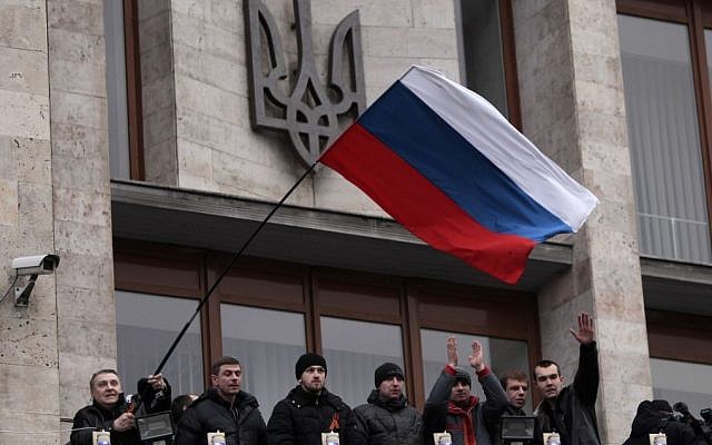 Pro-Russia demonstrators holding a Russian flag, with the Ukrainian emblem in the background, stand on the balcony of the regional administrative building after storming it in Donetsk, Ukraine, Wednesday, March 5, 2014. (photo credit: AP Photo/Sergei Chuzavkov) Pro-Russia demonstrators holding a Russian flag, with the Ukrainian emblem in the background, stand on the balcony of the regional administrative building after storming it in Donetsk, Ukraine, Wednesday, March 5, 2014. (photo credit: AP Photo/Sergei Chuzavkov)