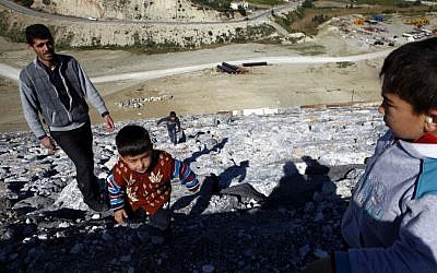 In this February 2014 photo, a man walks with his children on the side a massive dam in the northern Turkish Cypriot part in Panagra village of ethnically split Cyprus. (photo credit: AP Photo/Petros Karadjias)